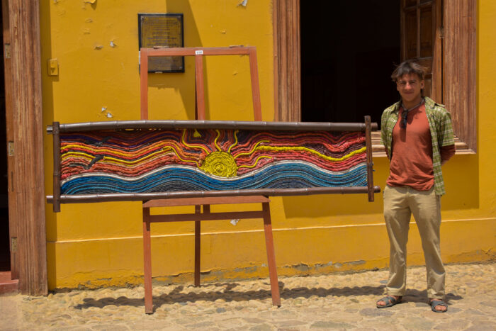 Kayosha Castro, fundado de Puémape Planet, al lado de un gran cuadro hecho con cuerdas de pescadores en desuso y llantas. Foto: Cortesía.